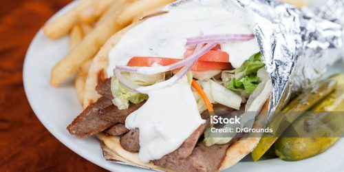 Plate with lamb gyro meat on pita bread served with french fries and pickles
