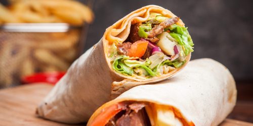 Side view shawarma with fried potatoes in board cookware on stone background