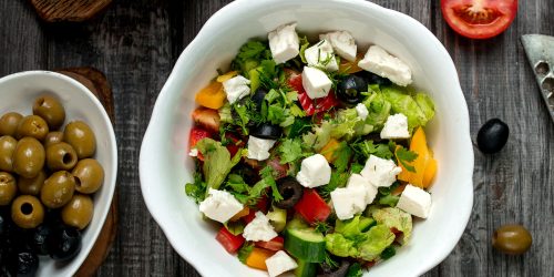 top view of greek salad bowl with white cheese bell peppers cucumber and tomato